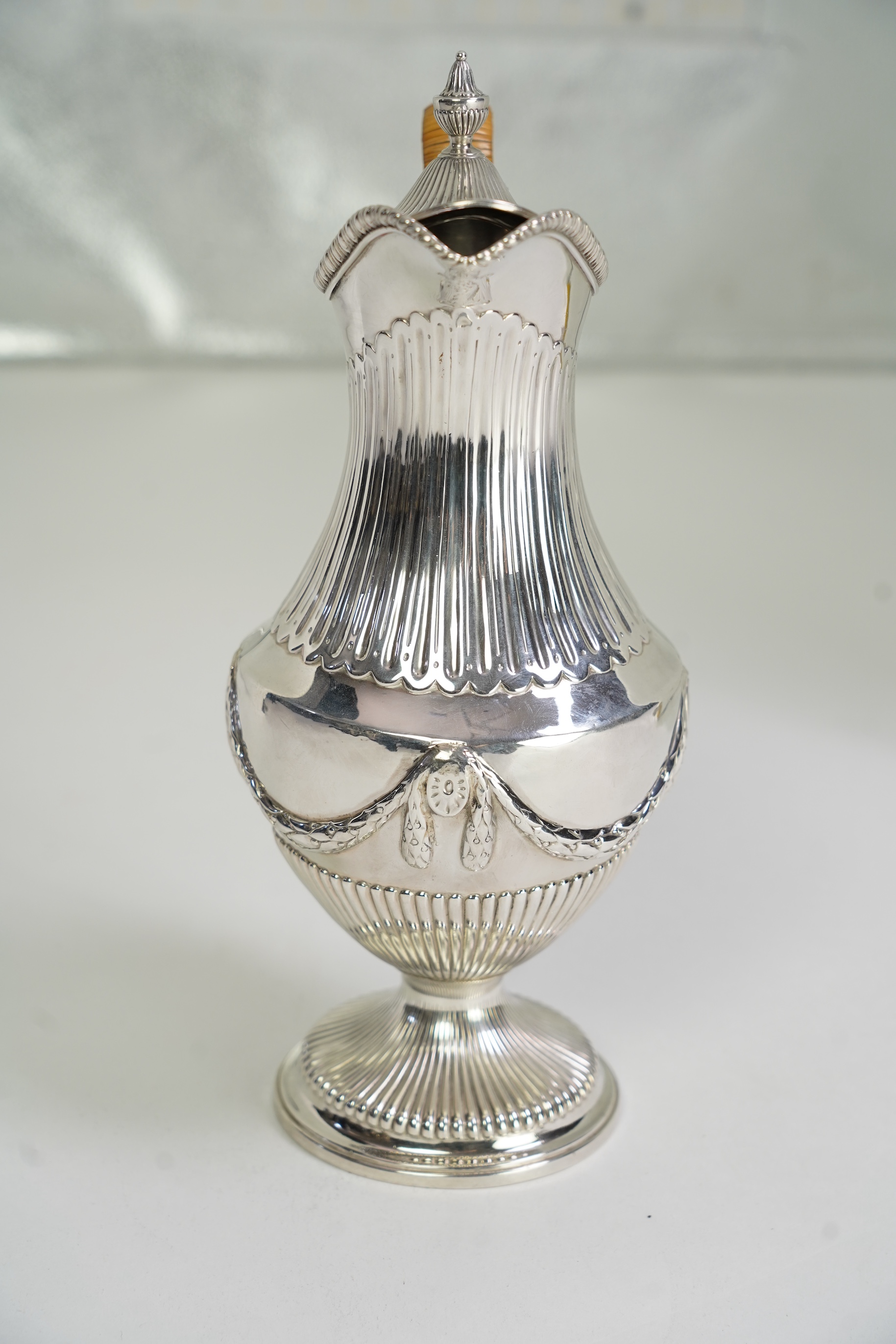 A George III neo-classical silver pedestal hot water pot, by Augustin Le Sage, engraved with the crest of The Right Reverend Robert Lowth, Bishop of London, (1710-1787)